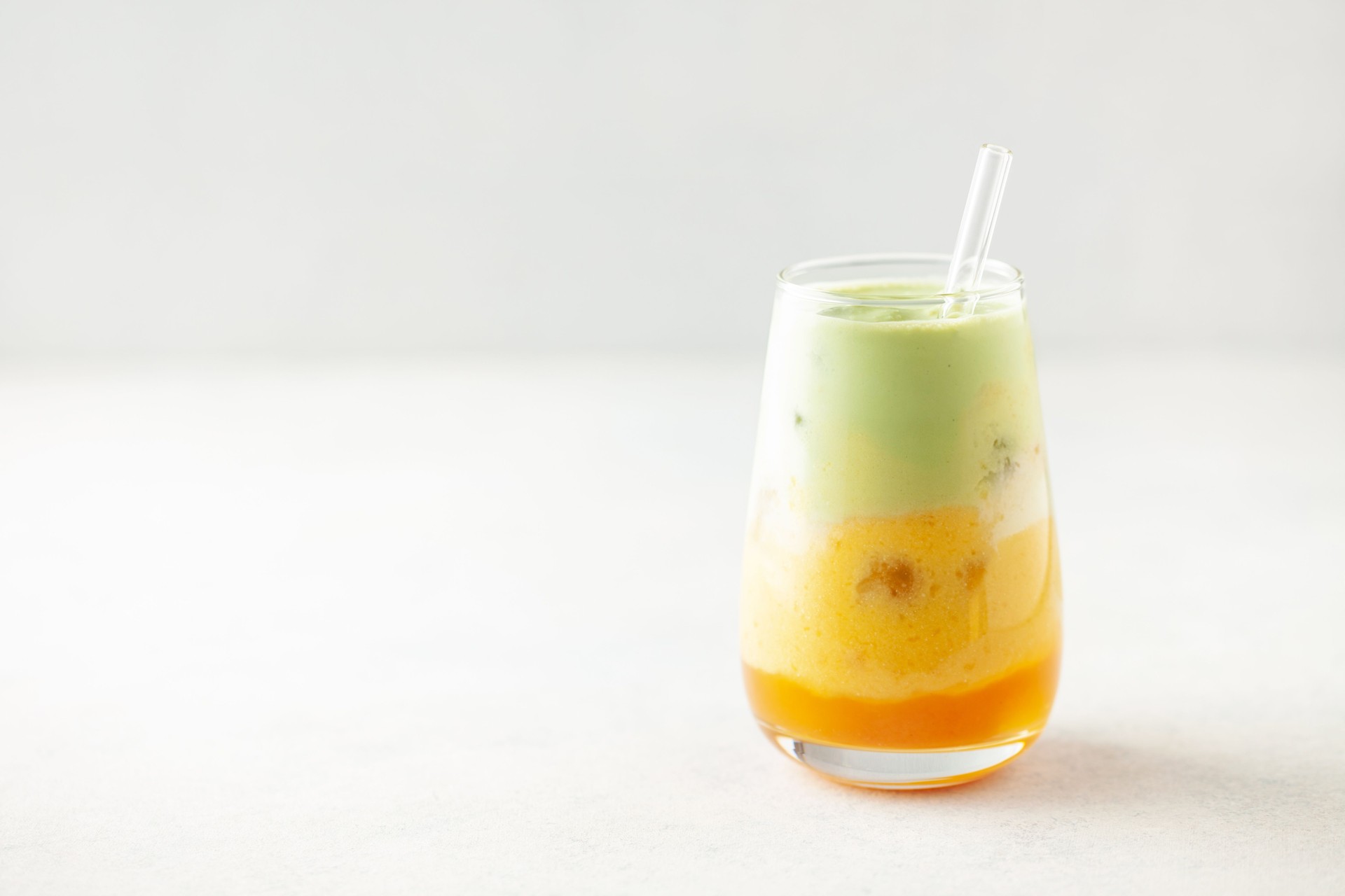 Iced mango matcha latte in glass on the table