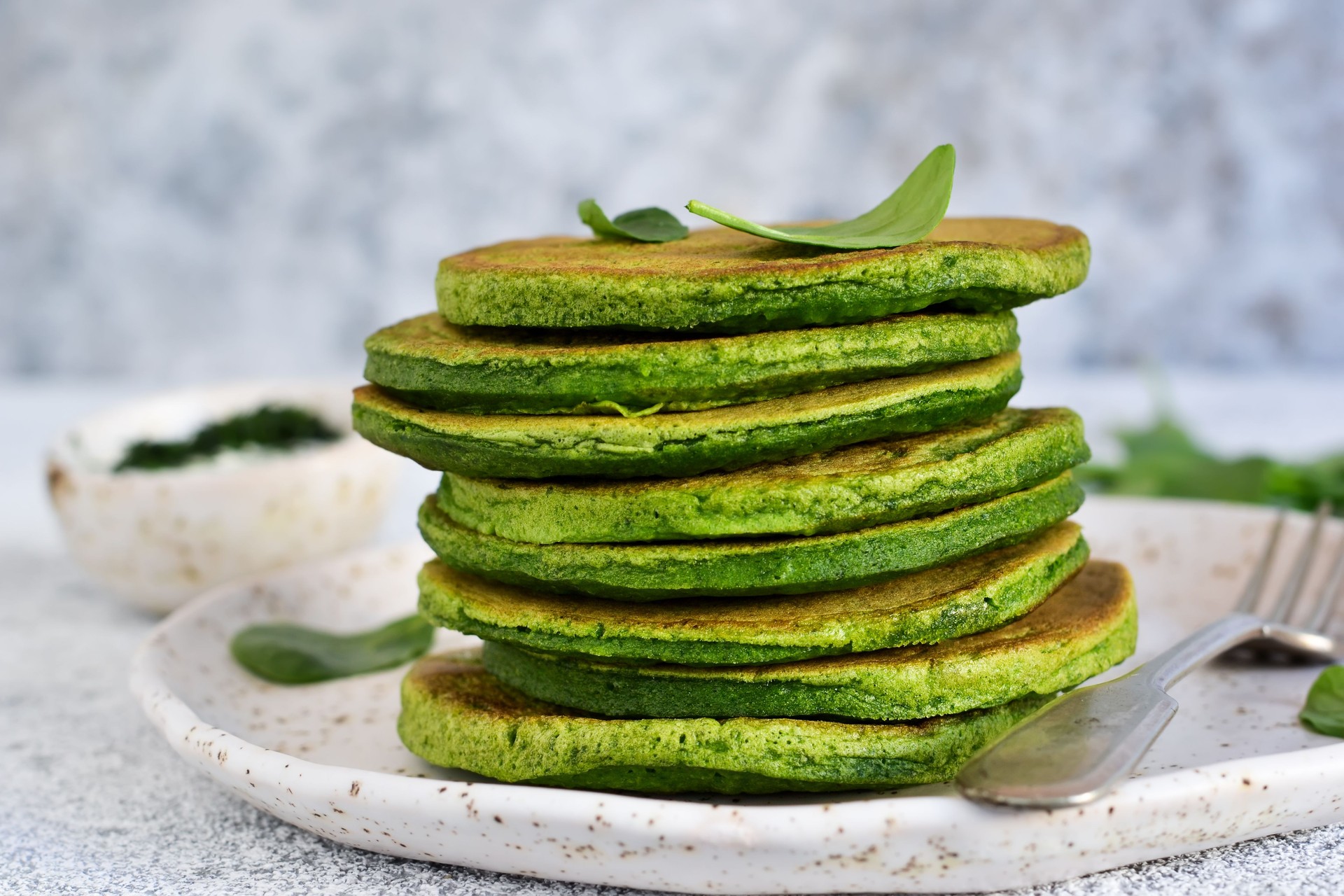 Green pancakes with spinach on a light concrete background. Classic breakfast.